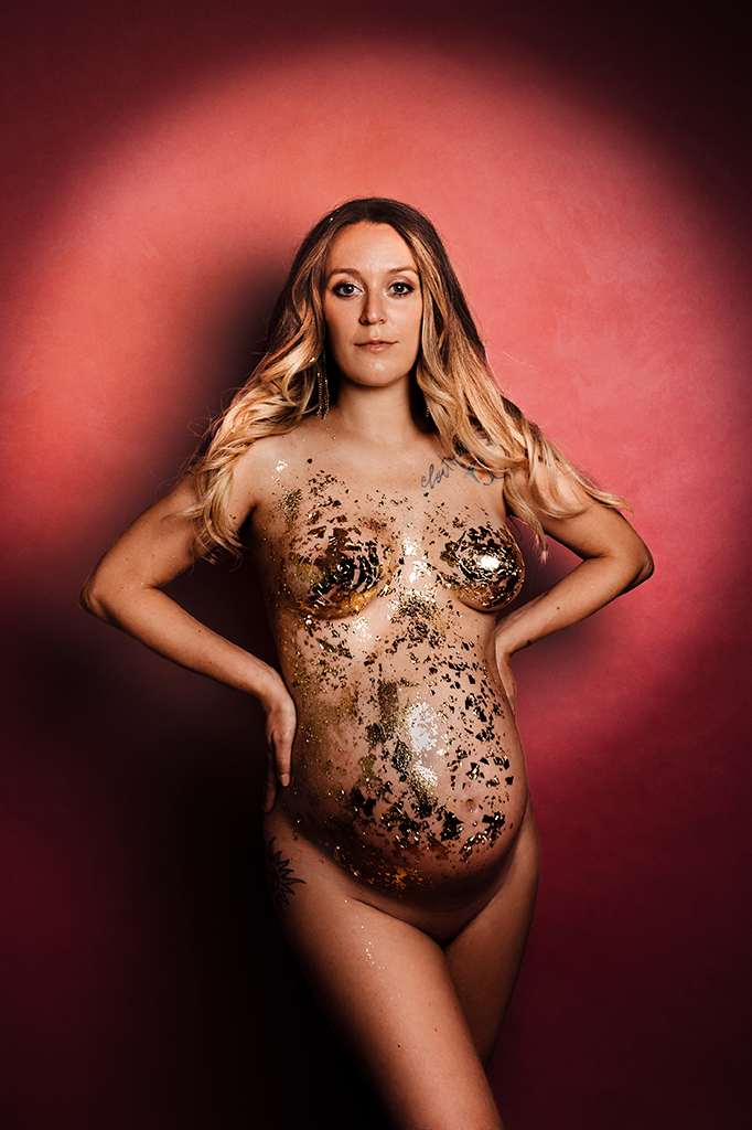 Foto Fine Art a colori di maternità di una donna bionda incinta nuda, con dell'oro addosso, su sfondo rosso. Fotografia Fine Art a colori di maternità di una donna bionda nuda con dell'oro addosso Italia