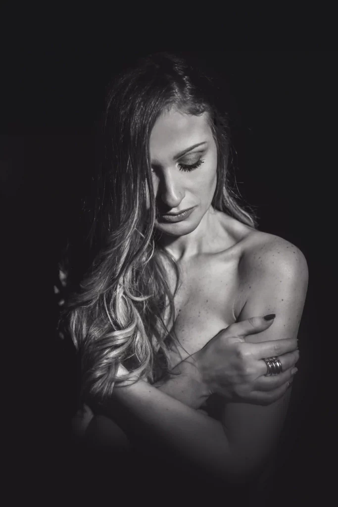 Foto artistica in bianco e nero di una donna che si avvolge dalle sue stesse braccia. Fotografia boudoir Italia